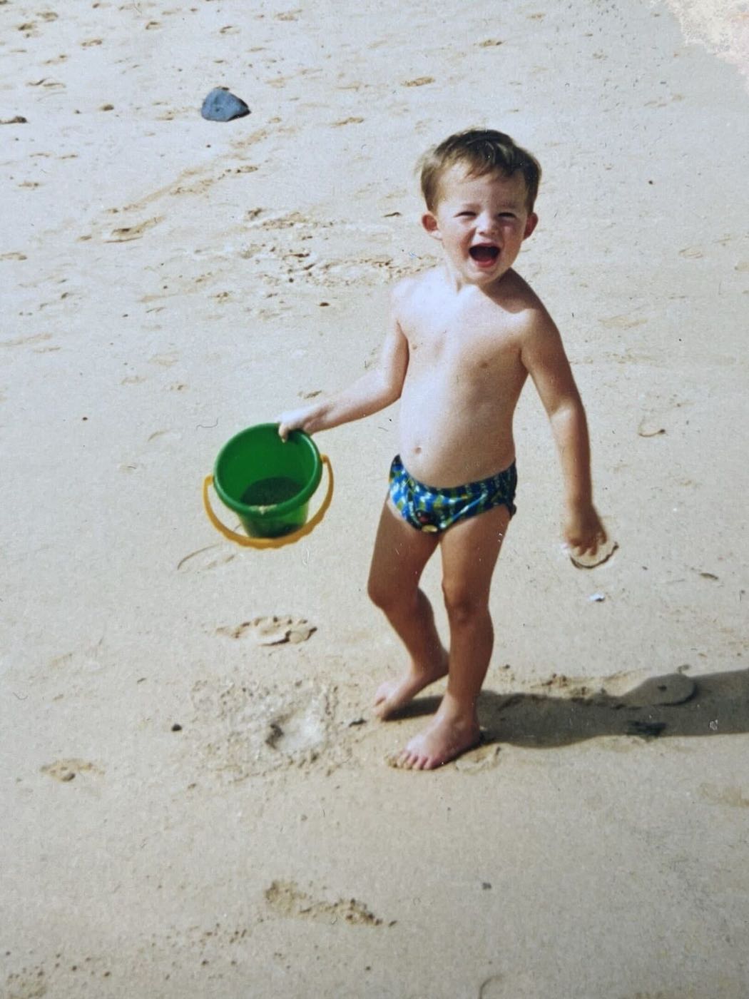 Ben as a toddler on the beach, bucket in hand