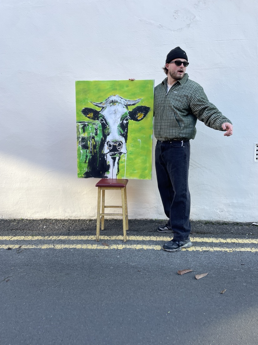 Ben holding his green cow painting, bold black outlines on acid green