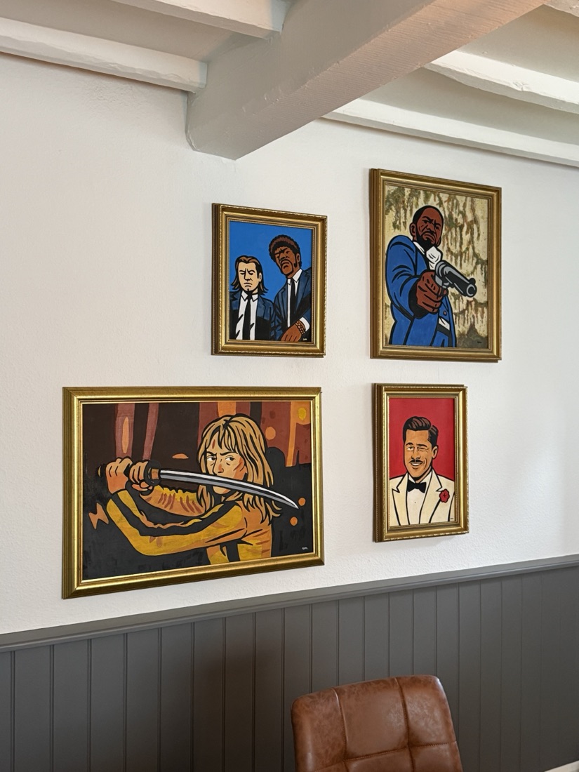 A wall of Ben's framed pop-culture portrait paintings: bold colour, hard outlines