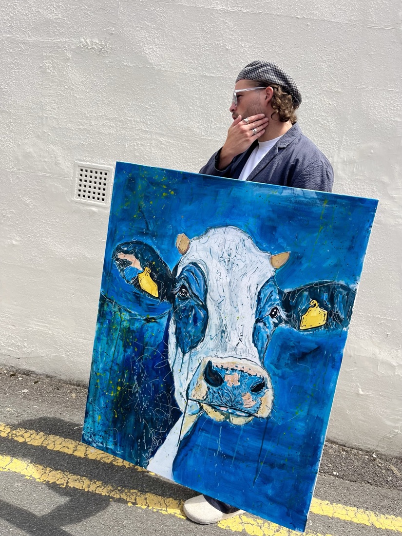 Ben holding his blue cow painting, bold outline over a deep blue ground