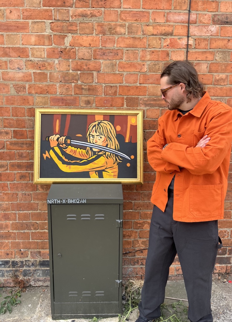 Ben holding a framed Kill Bill-inspired painting, bold colour and black outline