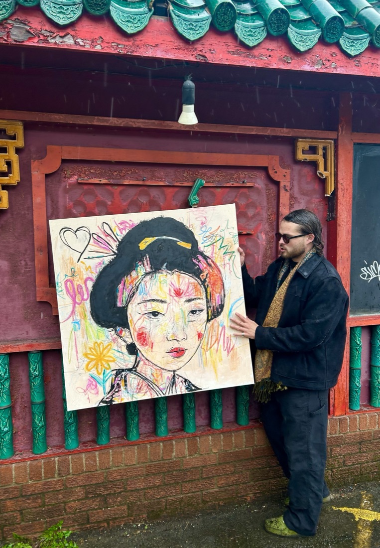 Ben holding a colourful mixed-media geisha portrait painting
