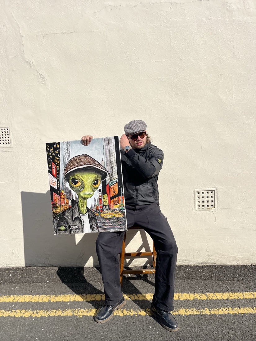 Ben holding his alien-in-the-city painting, bold colour and character
