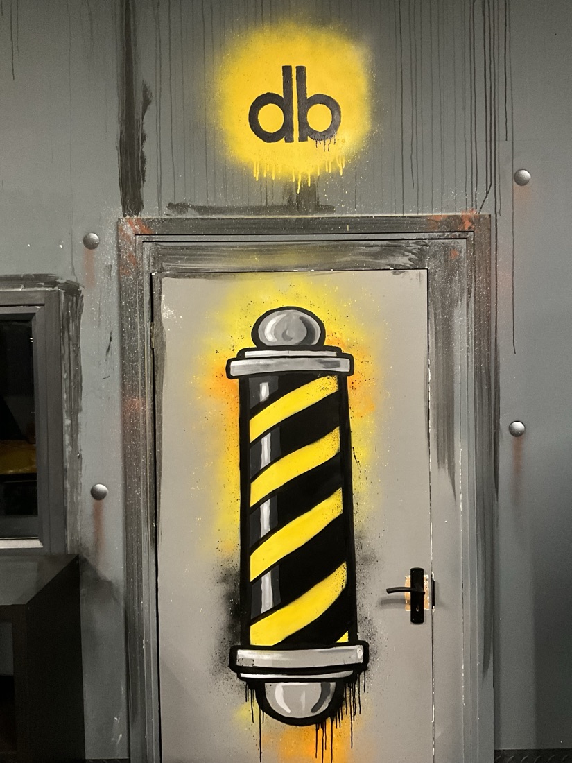 A hand-painted barber's pole and db logo mural on a doorway