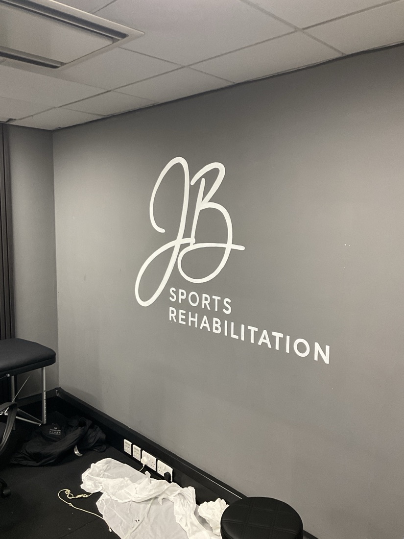 The JB Sports Rehabilitation logo, hand-painted in white on a grey wall