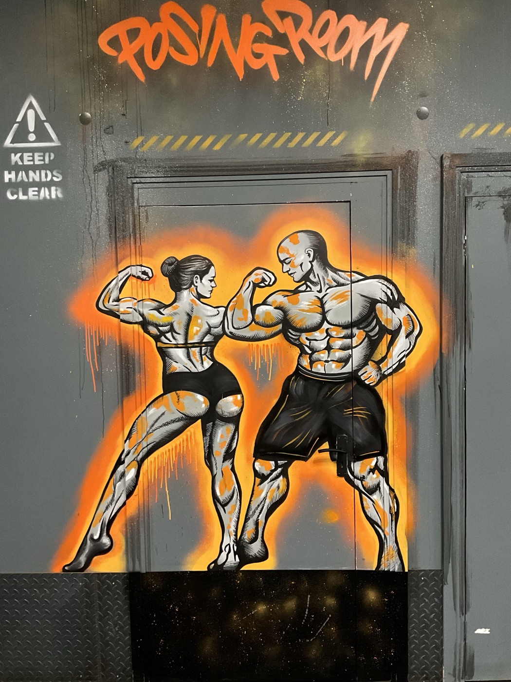 The ‘Posing Room’ mural at Foundry gym, two bodybuilders flexing in a burst of orange spray