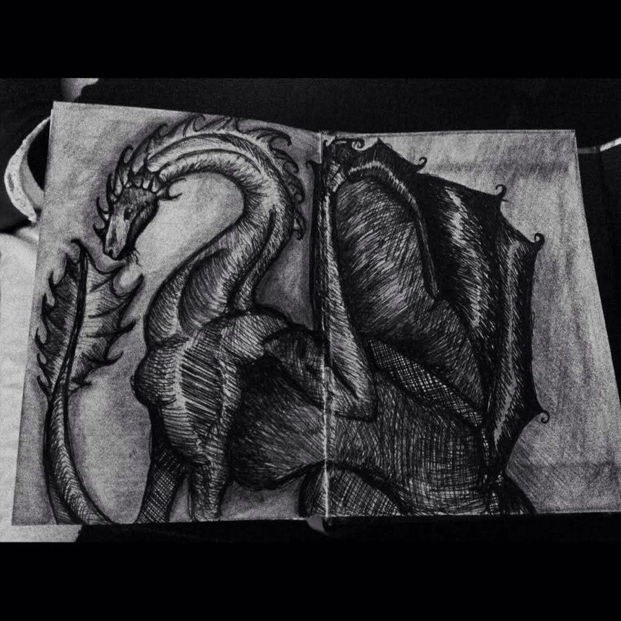 A detailed pencil drawing by Niamh of a dragon across two sketchbook pages