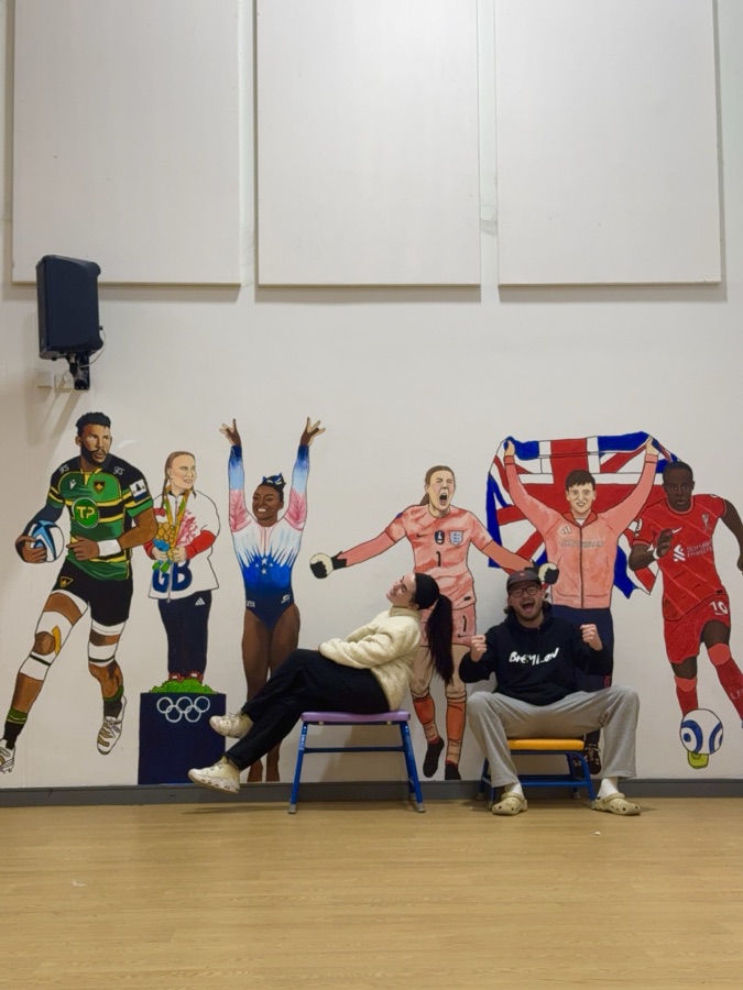 Ben and Niamh in front of the sports celebrity mural they created at Pineham Primary School