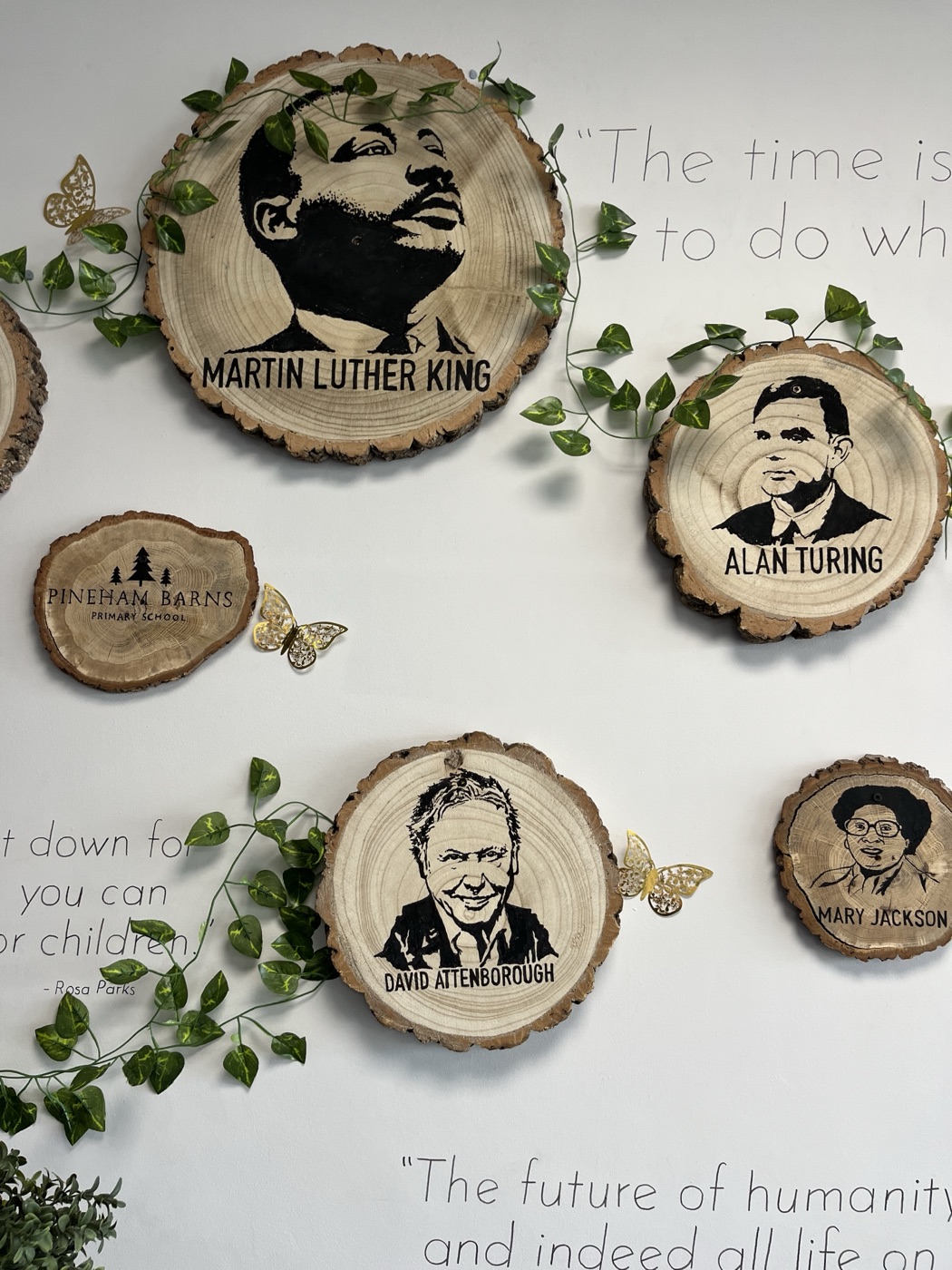 A school wall of hand-painted wood-slice portraits: Martin Luther King, Alan Turing, David Attenborough and more