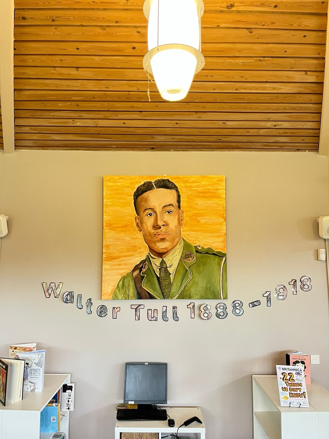 A large painted canvas portrait of Walter Tull (1888–1918) hanging in a school library