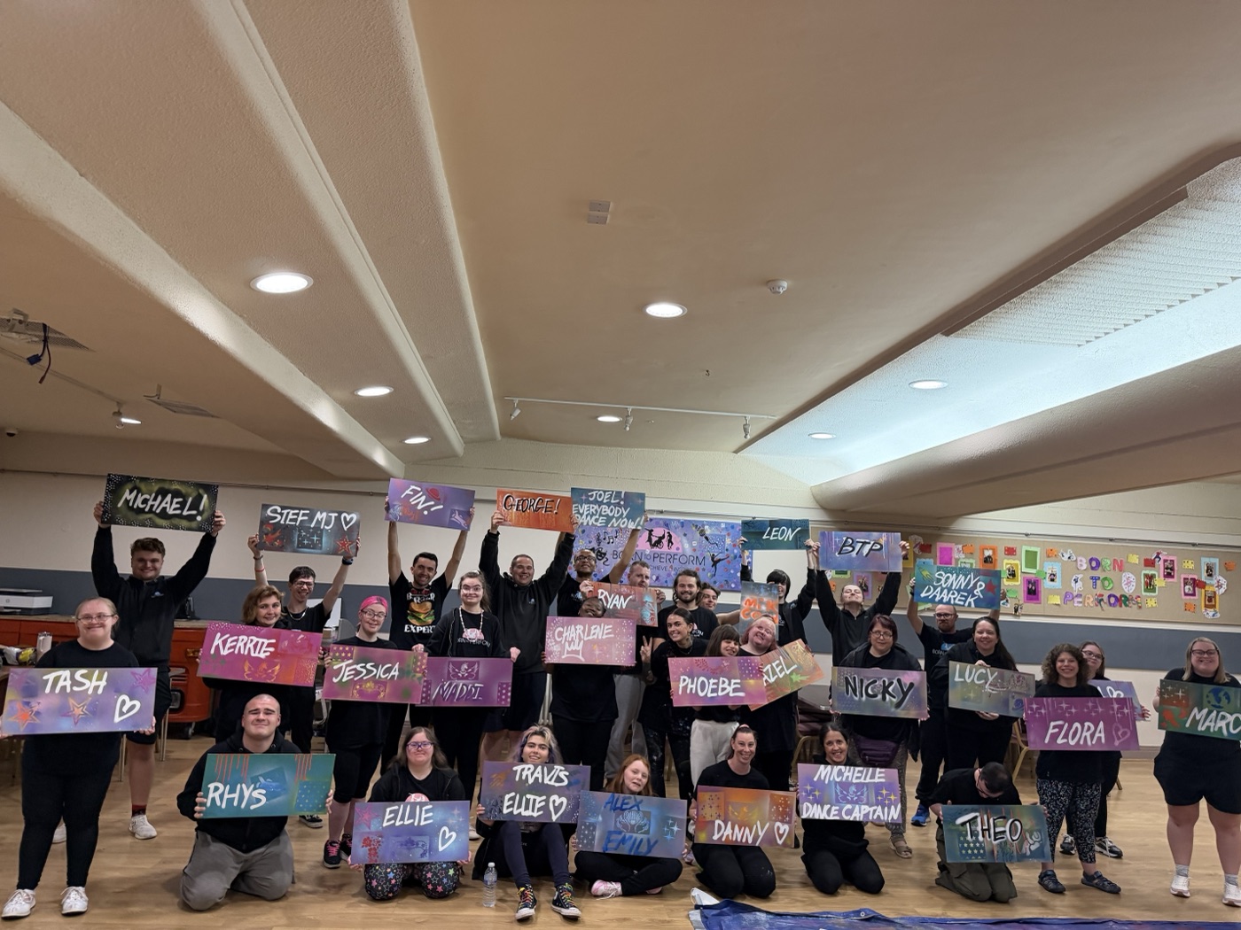 The full Born to Perform group holding up the name boards they spray-painted with Patricia Studios