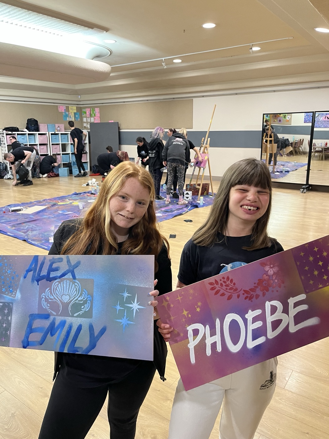 Two Born to Perform artists holding up the name boards they spray-painted