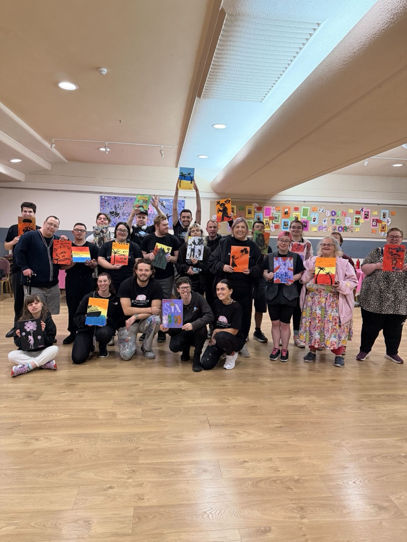A full workshop group holding up their finished paintings, everyone made something